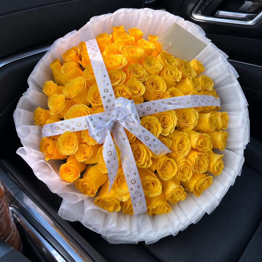 Bouquet of yellow roses wrapped in white paper with a ribbon
