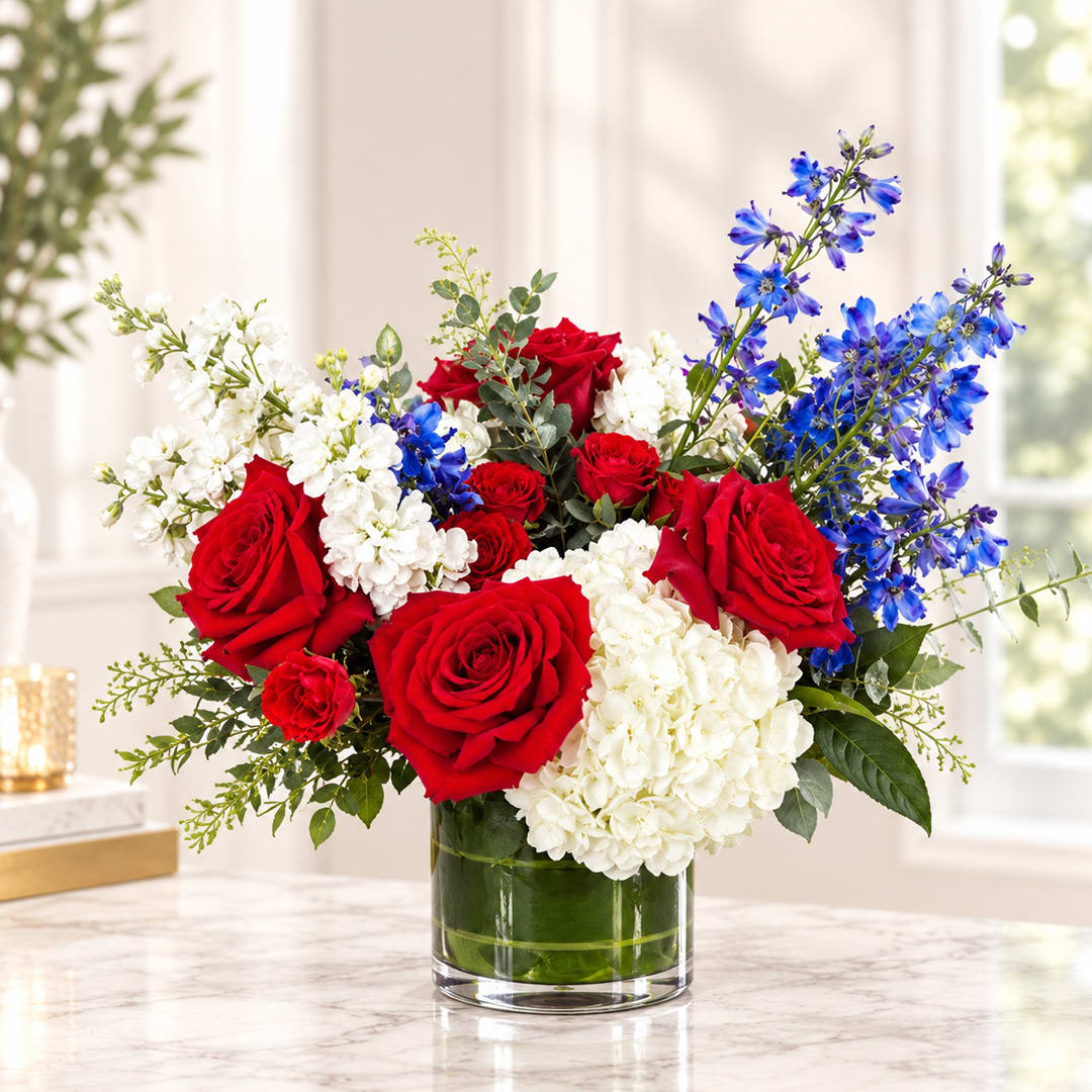 Red roses, white hydrangeas, and blue flowers in a glass vase