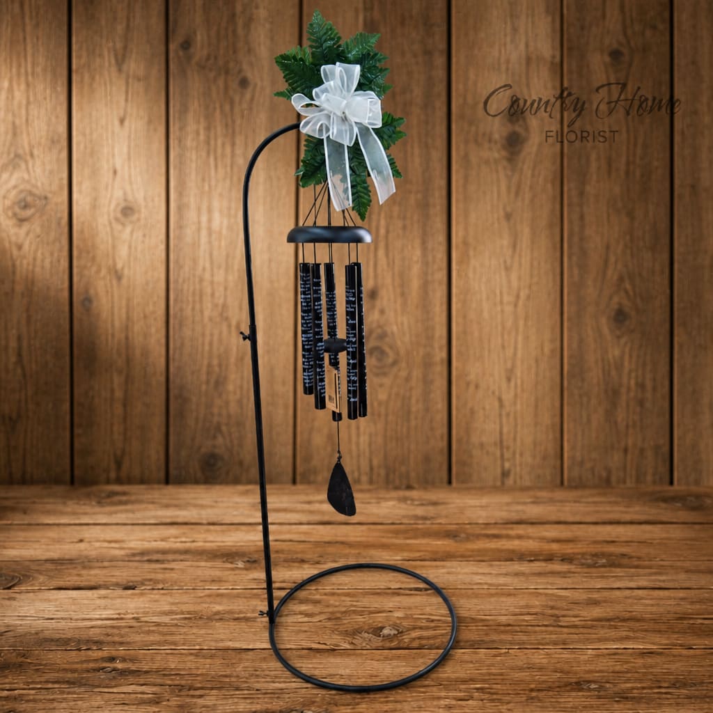 Black metal wind chime with green foliage and a white bow