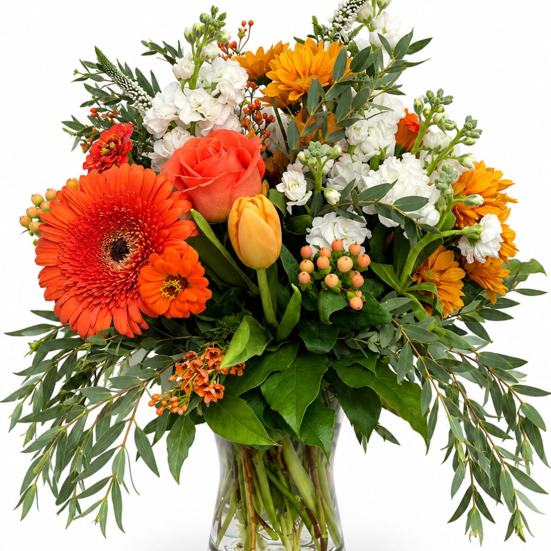 Mixed bouquet of orange, white, and yellow flowers in a clear glass vase