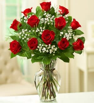 Red roses arranged in a clear glass vase with baby's breath