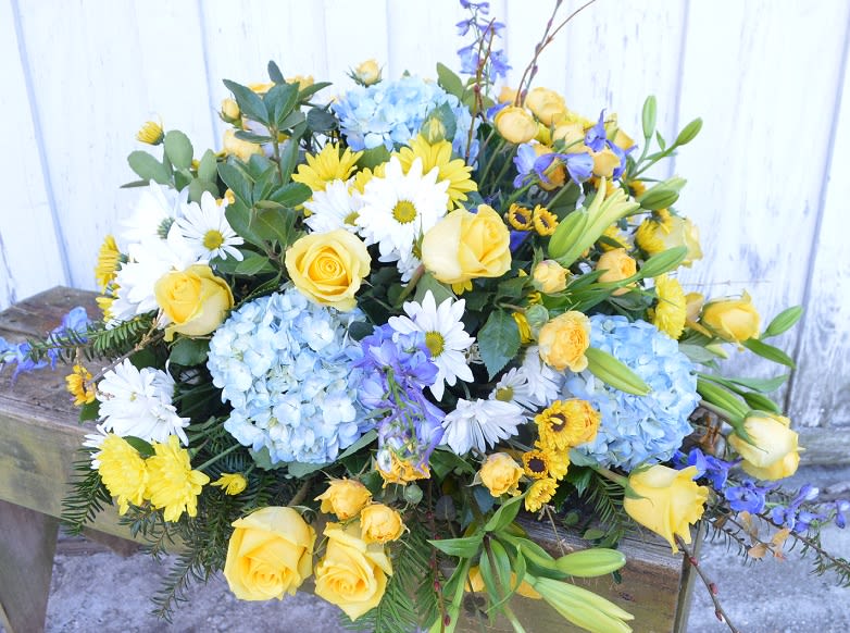 Bouquet of yellow roses, blue hydrangeas, and white daisies