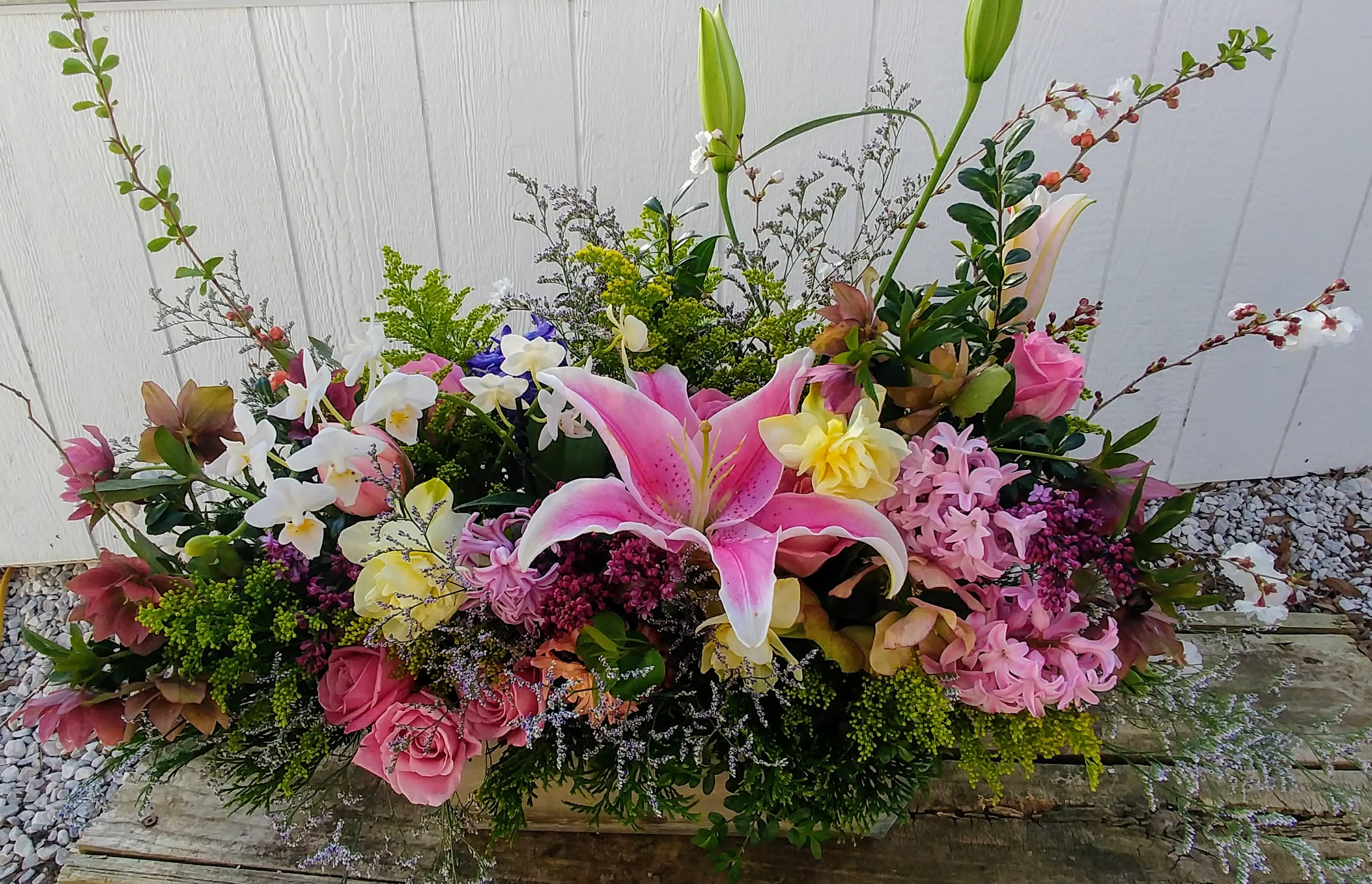 Large mixed floral arrangement with pink lilies and roses in a low container
