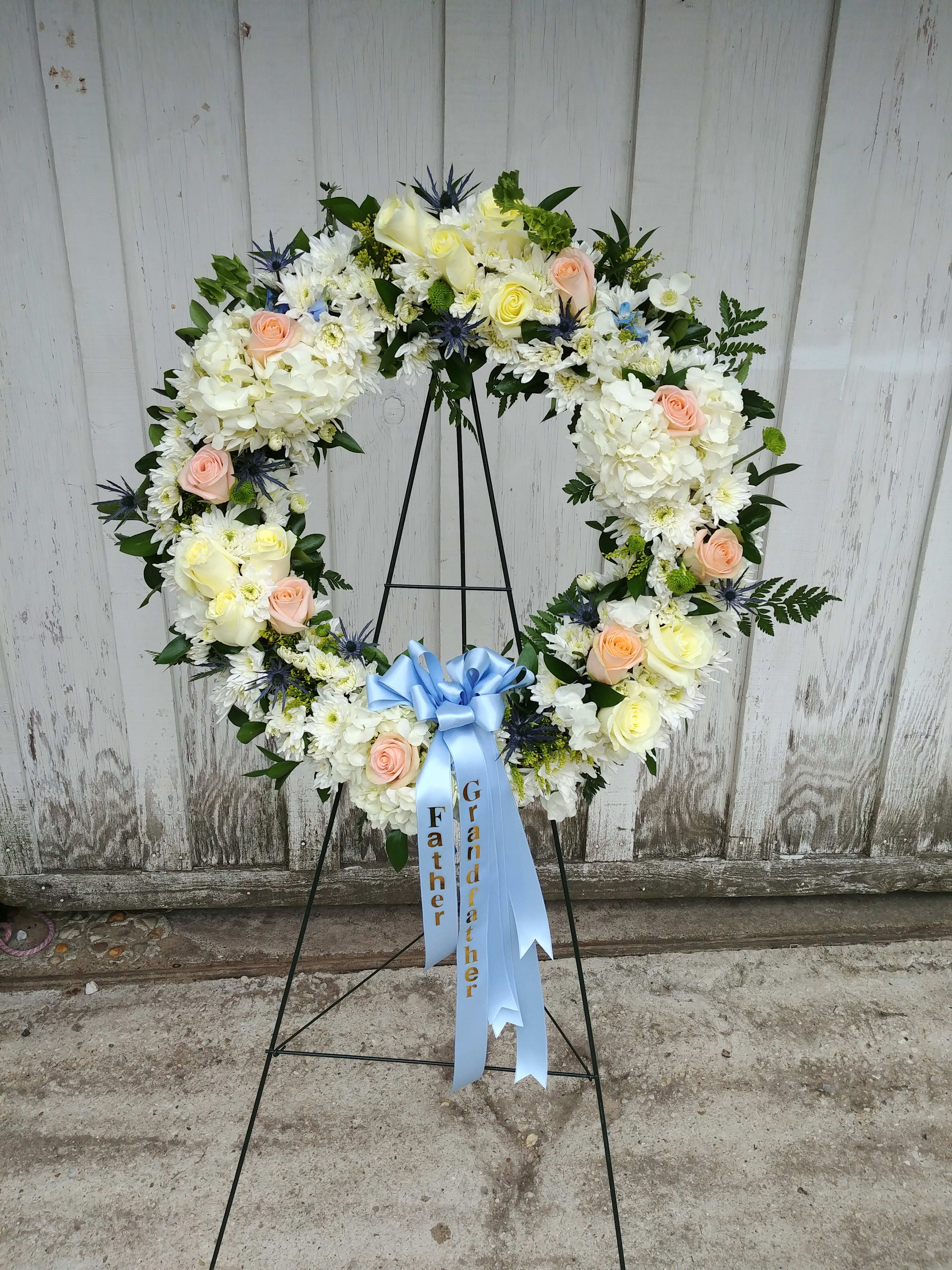 Heart-shaped floral wreath with white and peach flowers on a stand
