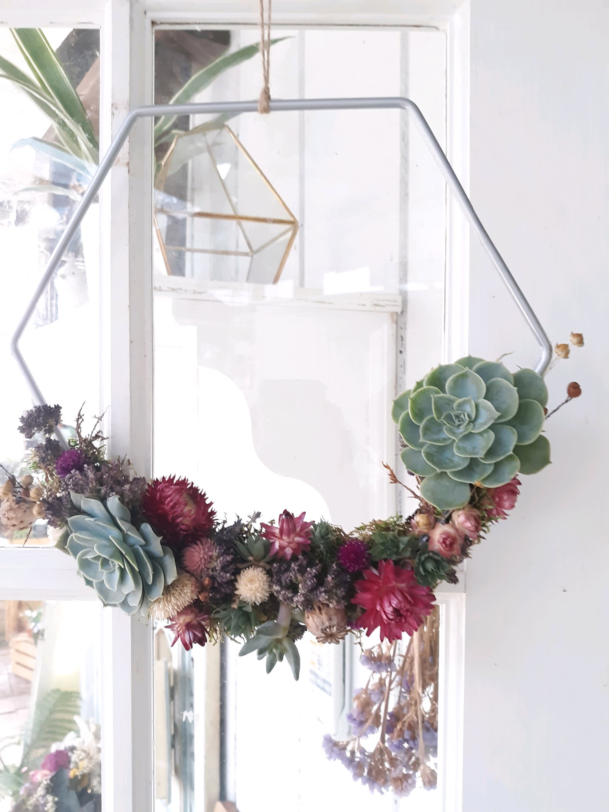 Succulent wreath with pink and purple dried flowers on a metal frame