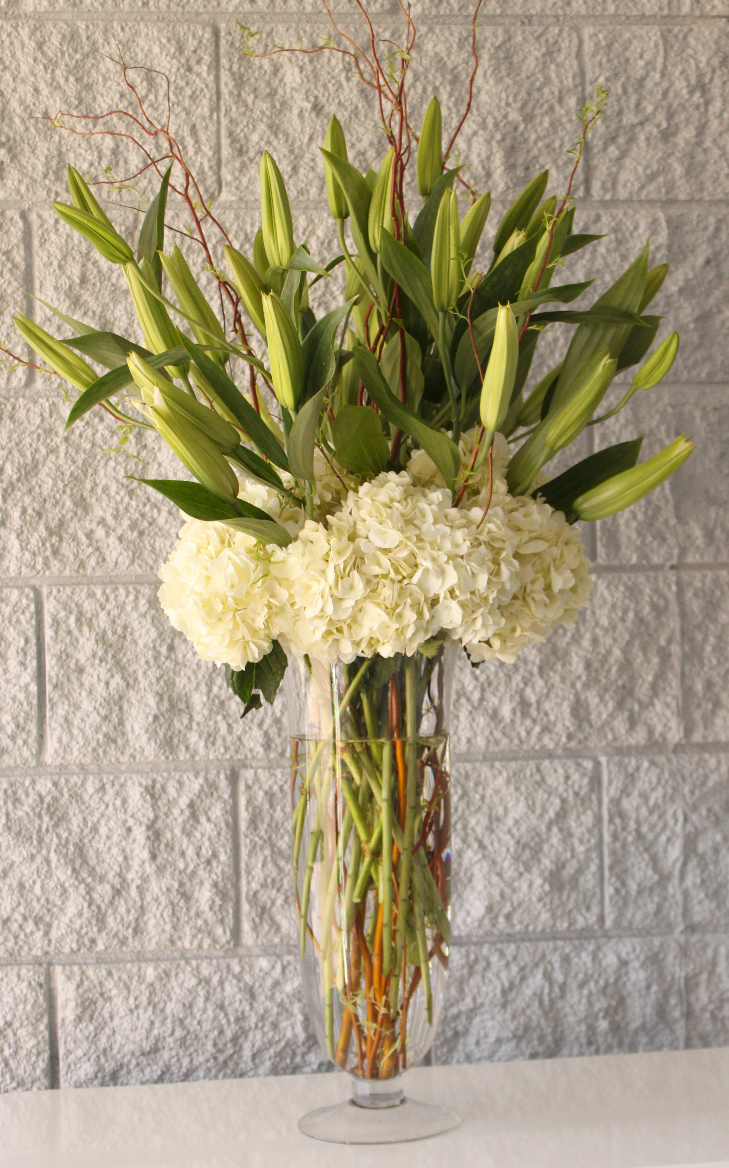 White lilies and hydrangeas in a tall glass vase