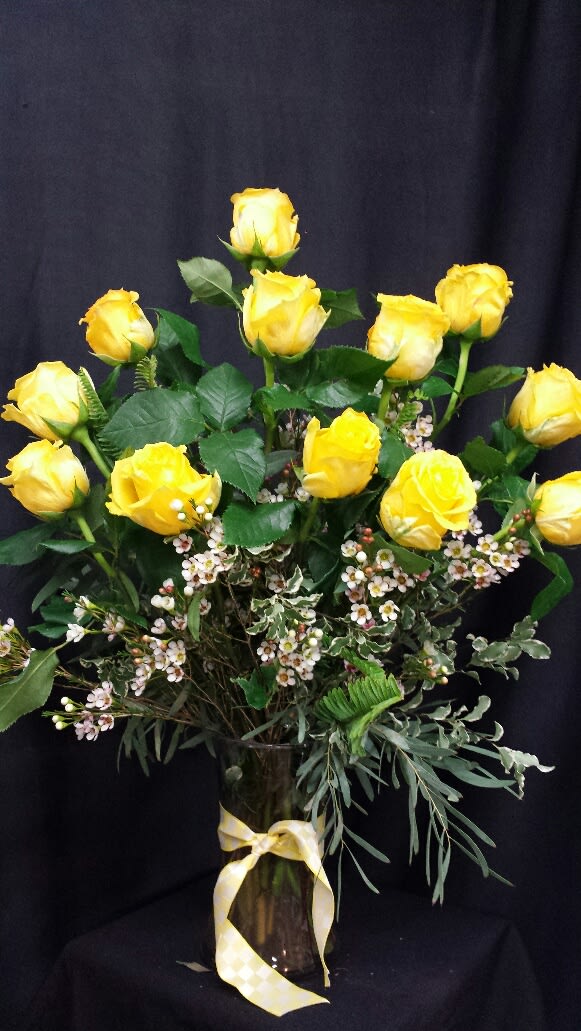 Yellow roses arranged in a glass vase with a ribbon
