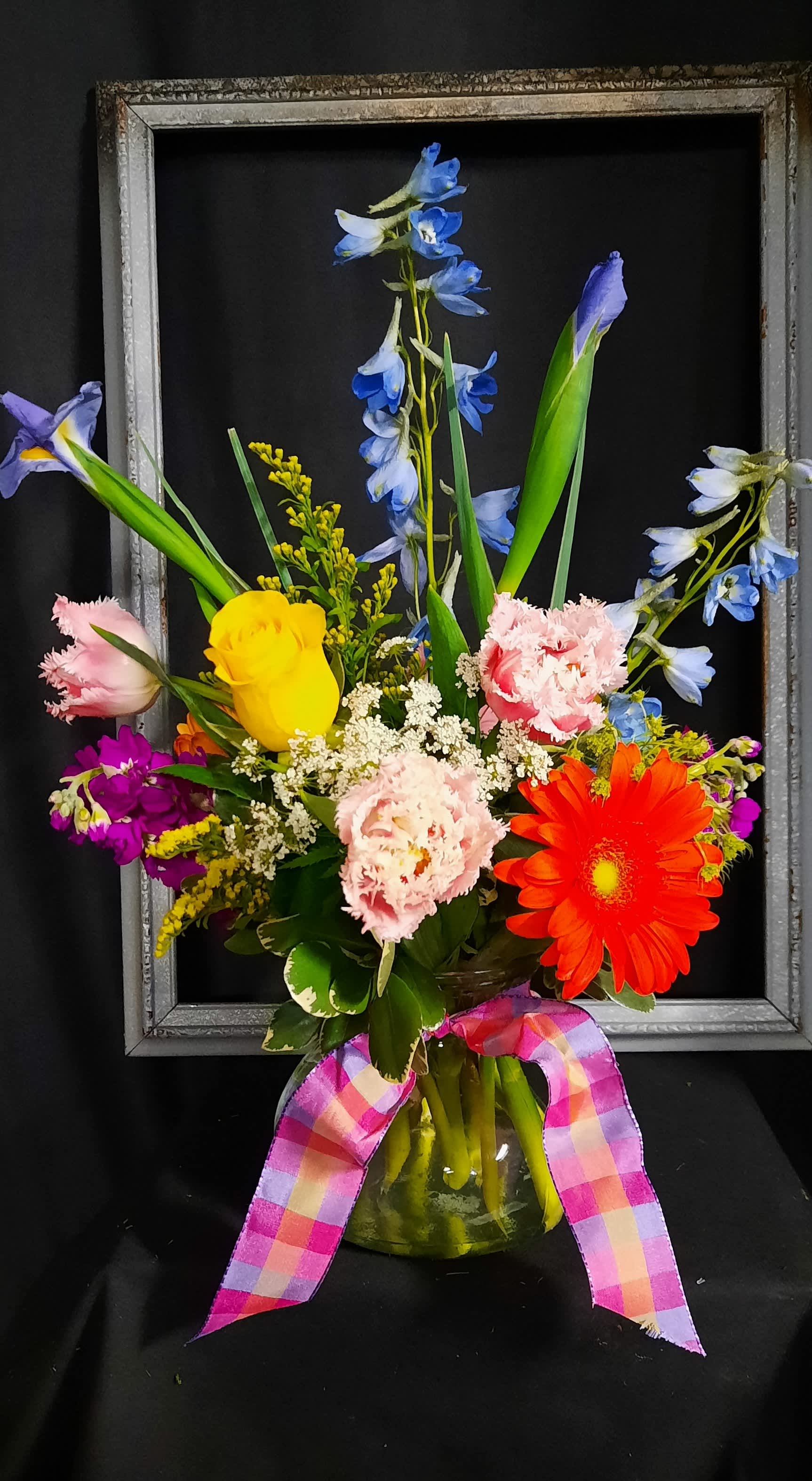 Colorful mixed bouquet in a glass vase with a plaid ribbon