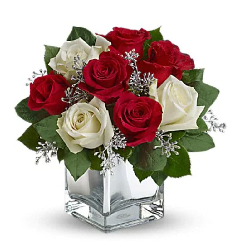 Red and white roses arranged in a clear square vase