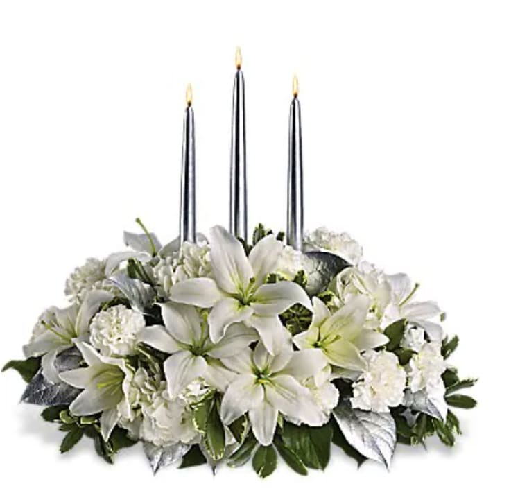 White floral centerpiece with three tall taper candles