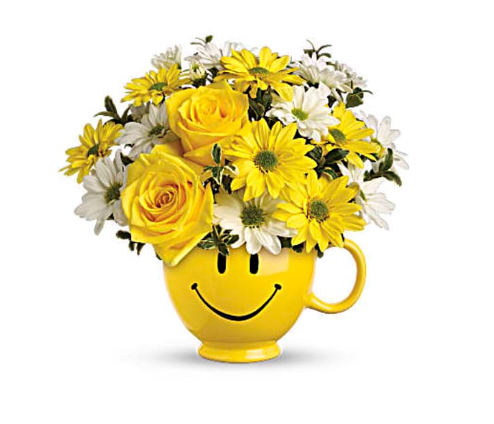 Yellow and white flowers arranged in a smiley-face mug