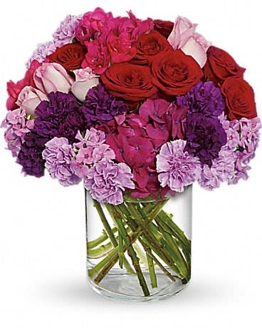Bouquet of red roses and pink-purple flowers in a clear glass vase