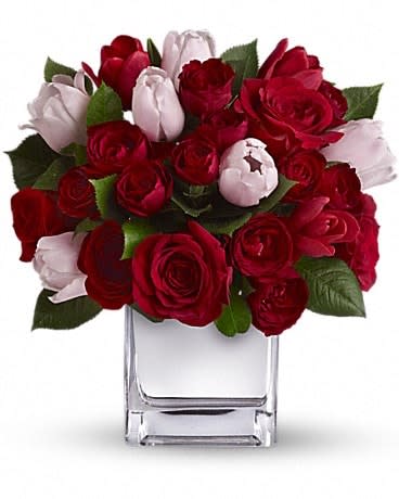 Red and pale pink roses arranged in a clear square vase