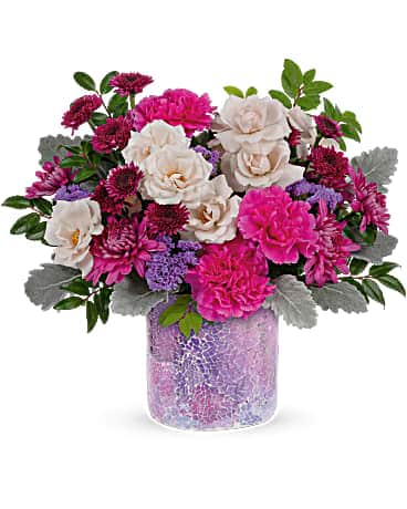 Shining Beauty Bouquet - Glam it up! Make mom feel extra special this ravishing rose bouquet, presented to perfection in a keepsake vase of mosaic glass that sparkles in the most magnificent shades of lavender! This bouquet includes cream spray roses, purple button spray chrysanthemums, hot pink carnations, purple cushion spray chrysanthemums, lavender sinuata statice, dusty miller and huckleberry. Delivered in a Shining Beauty cylinder.