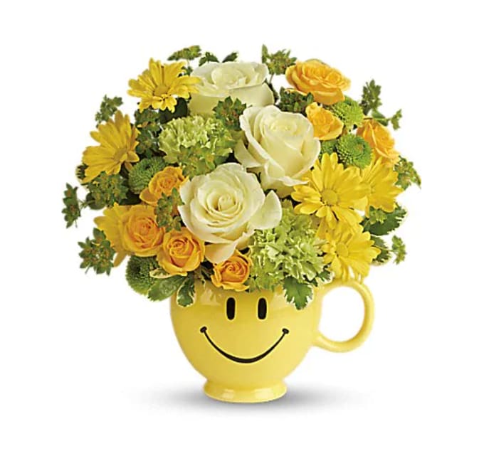 You Make Me Smile Bouquet - Put a smile on their face - and in their heart - with this happy as can be bouquet! Hand-delivered in a food safe mug for years of satisfied sipping, this cheerful gift of roses and mums spreads happiness wherever it goes. This cheerful bouquet includes light yellow roses, yellow spray roses, green carnations, green button spray chrysanthemums, yellow daisy spray chrysanthemums, bupleurum and variegated pittosporum. Delivered in a Be Happy mug. 