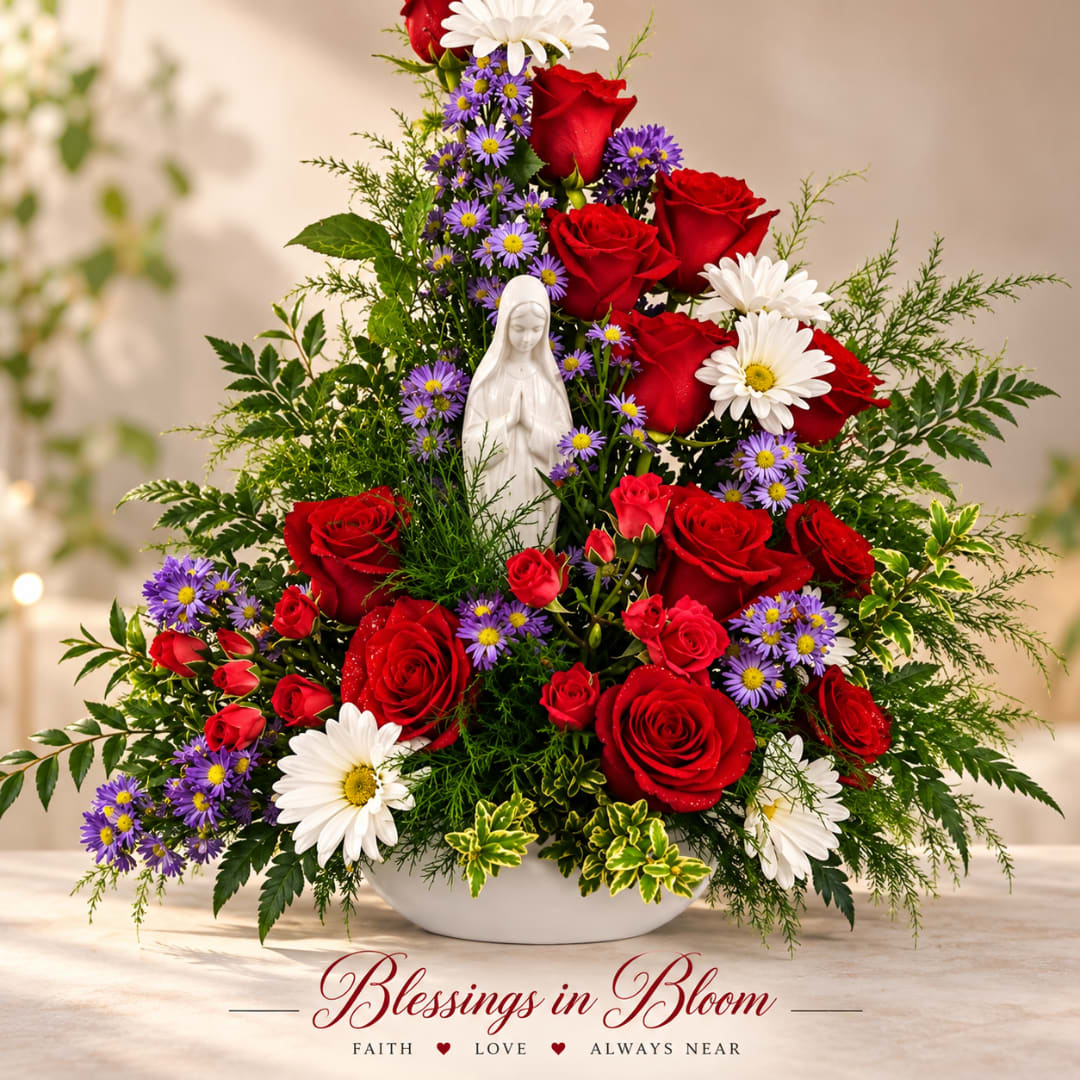 Red roses and white daisies arranged around a small white statue in a bowl vase