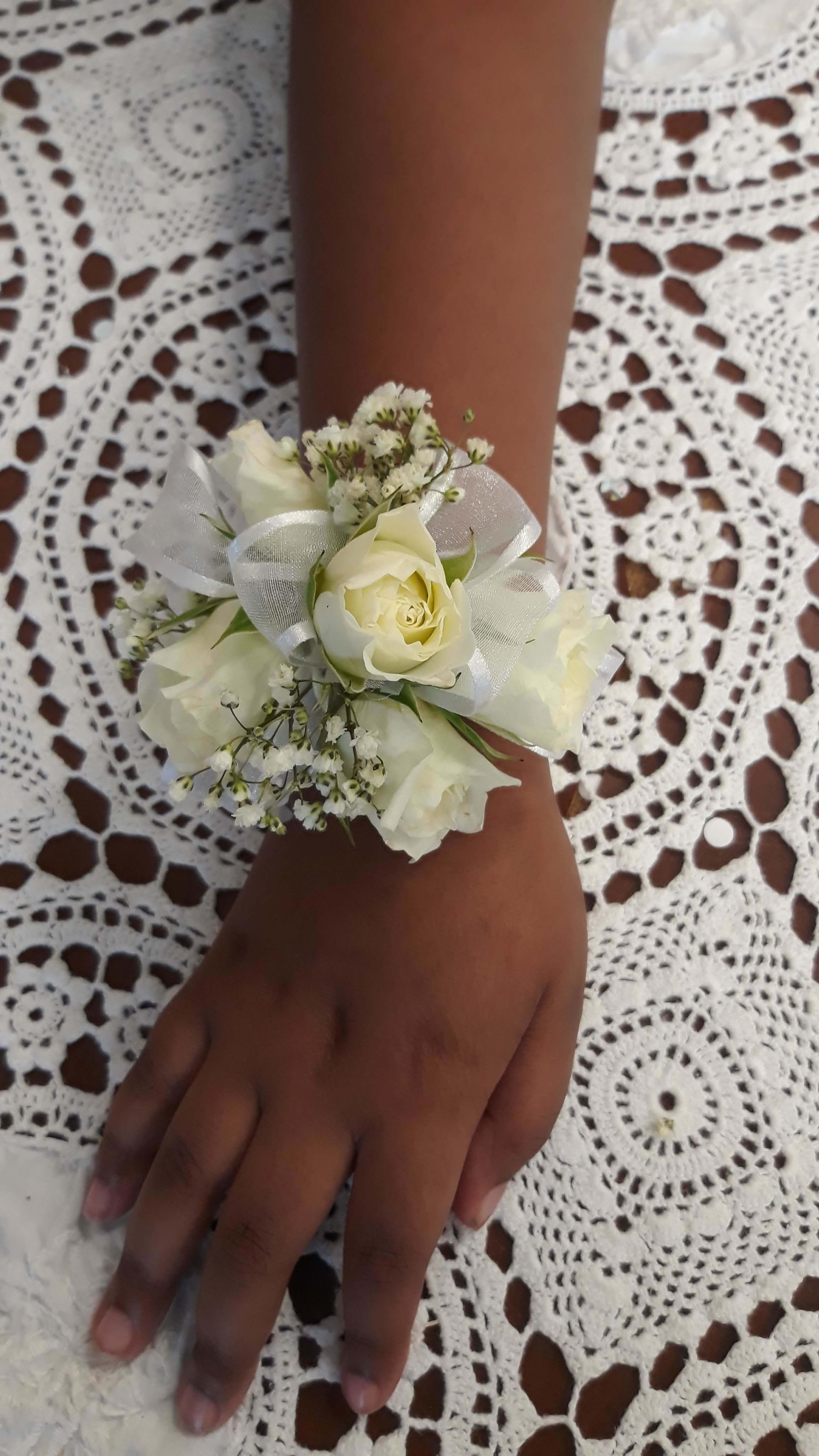White rose wrist corsage with ribbon on a person's wrist