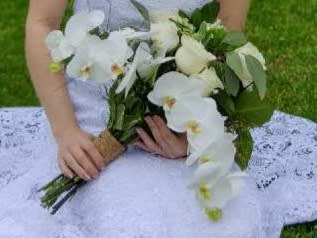 Bride holding a white orchid bouquet with greenery