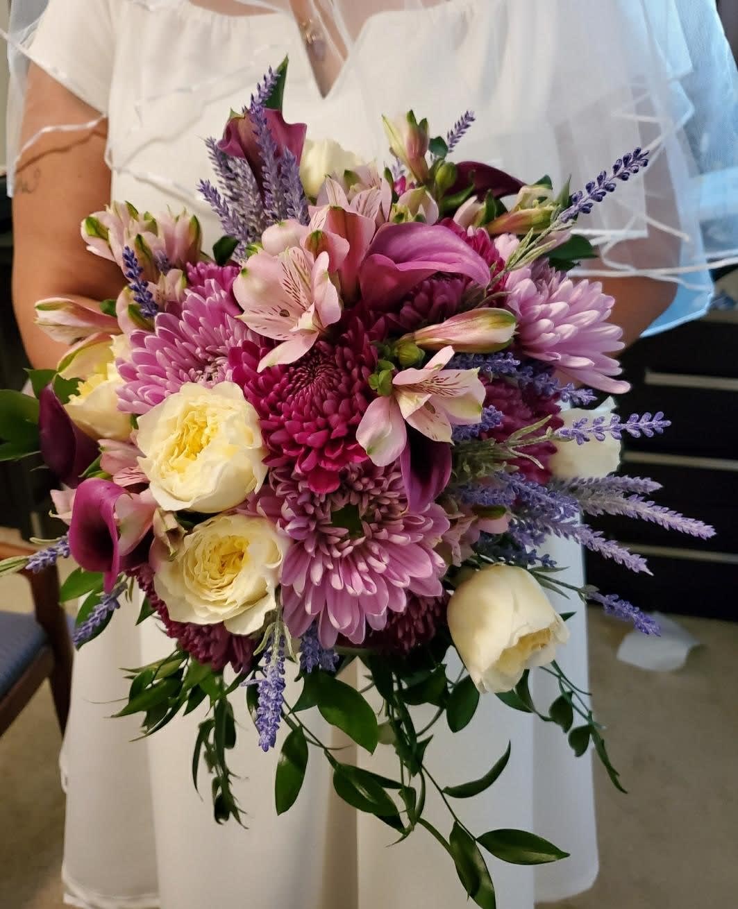Bride holding a pink and cream bouquet with purple accents