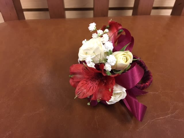 Small bouquet of white and red flowers with a purple ribbon