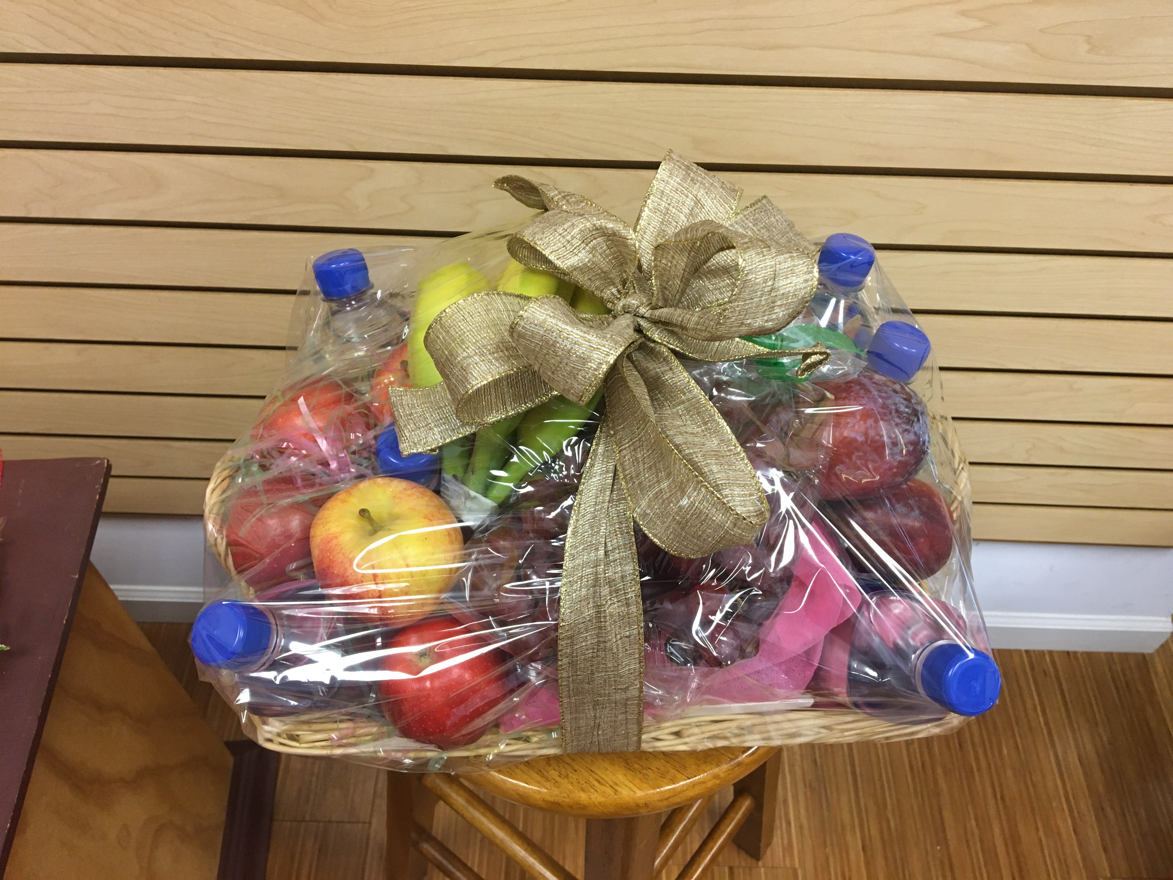 Fruit basket wrapped in plastic with a gold bow