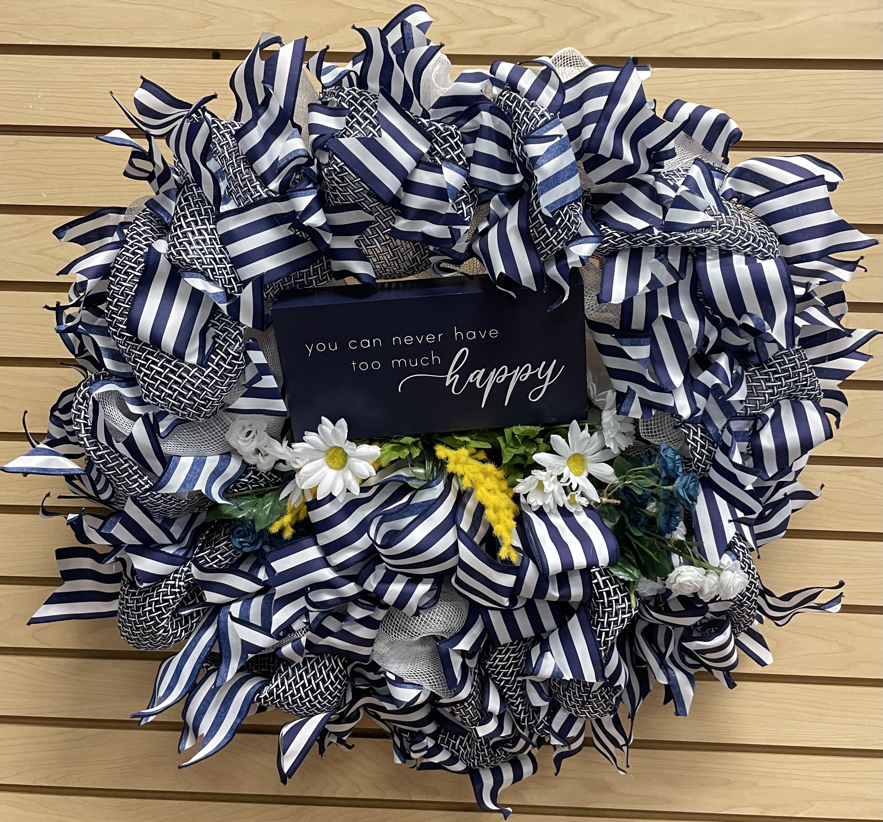 Blue-and-white ribbon wreath with small daisies and a happy sign