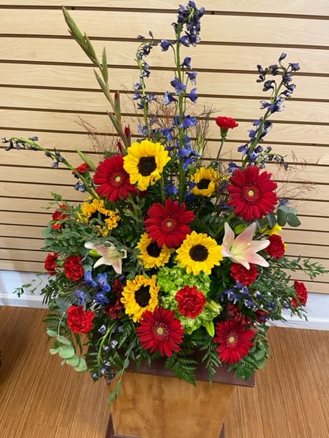 Tall mixed flower arrangement with sunflowers, red gerberas, and lilies