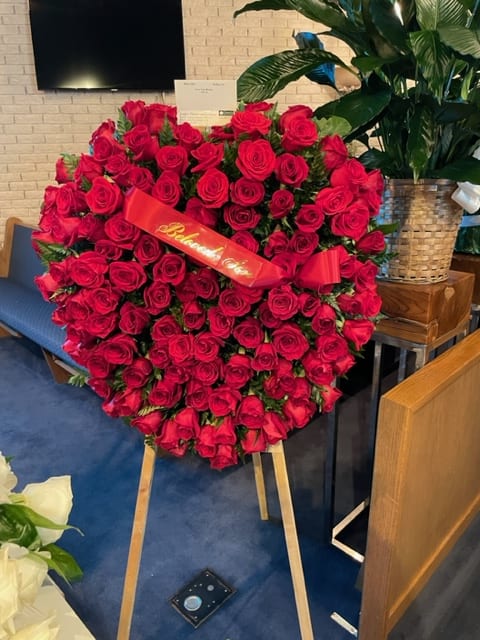 Large heart-shaped arrangement of red roses on an easel with a ribbon