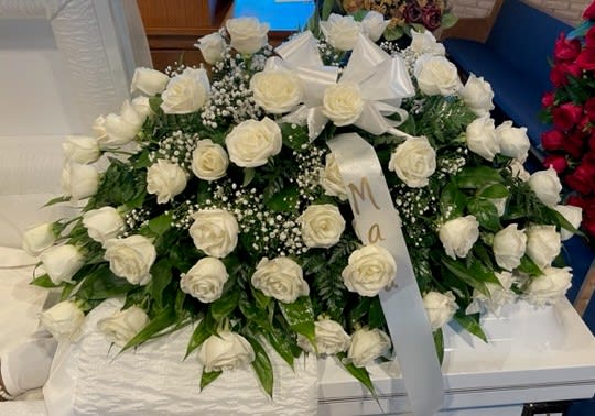 Large white rose casket spray with ribbon bows and baby's breath