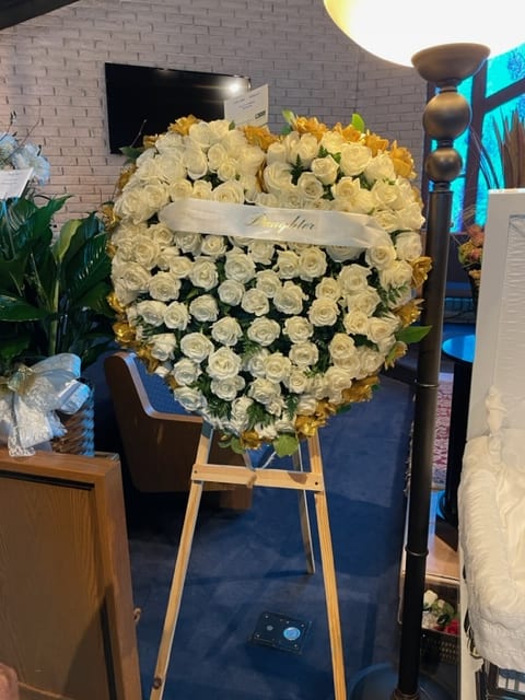 Heart-shaped white rose arrangement on an easel with gold accents