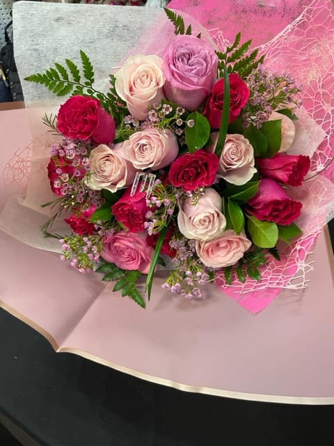 Bouquet of pink, lavender, and white roses wrapped in pink paper
