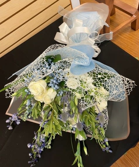 Bouquet of white and blue flowers wrapped in mesh and ribbon