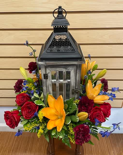Lantern centerpiece surrounded by red roses and yellow lilies