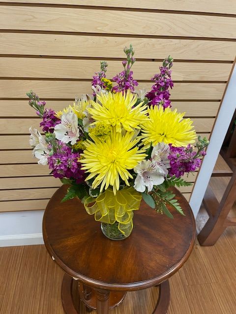 Bouquet of yellow chrysanthemums and purple flowers in a glass vase
