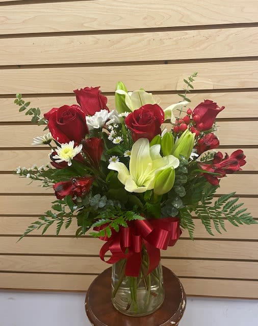 Red roses and white lilies in a glass vase with a red ribbon