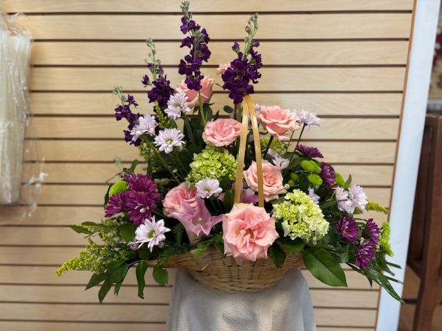 Basket arrangement of pink roses and purple flowers
