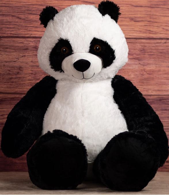 Plush panda bear sitting against a wood background