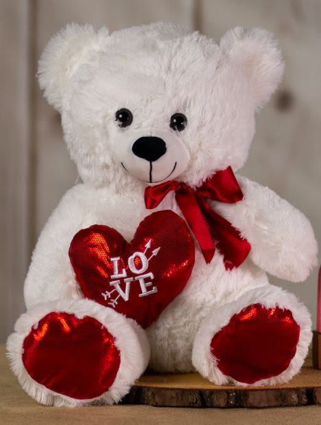 White teddy bear holding a red heart with a ribbon