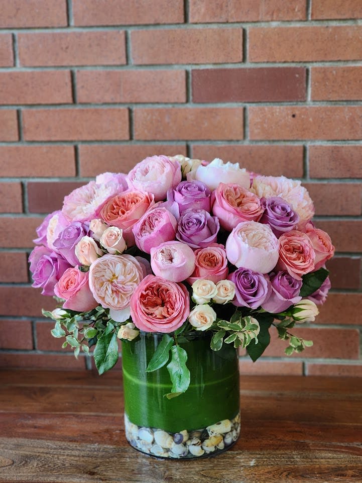 Pink and lavender roses arranged in a glass vase