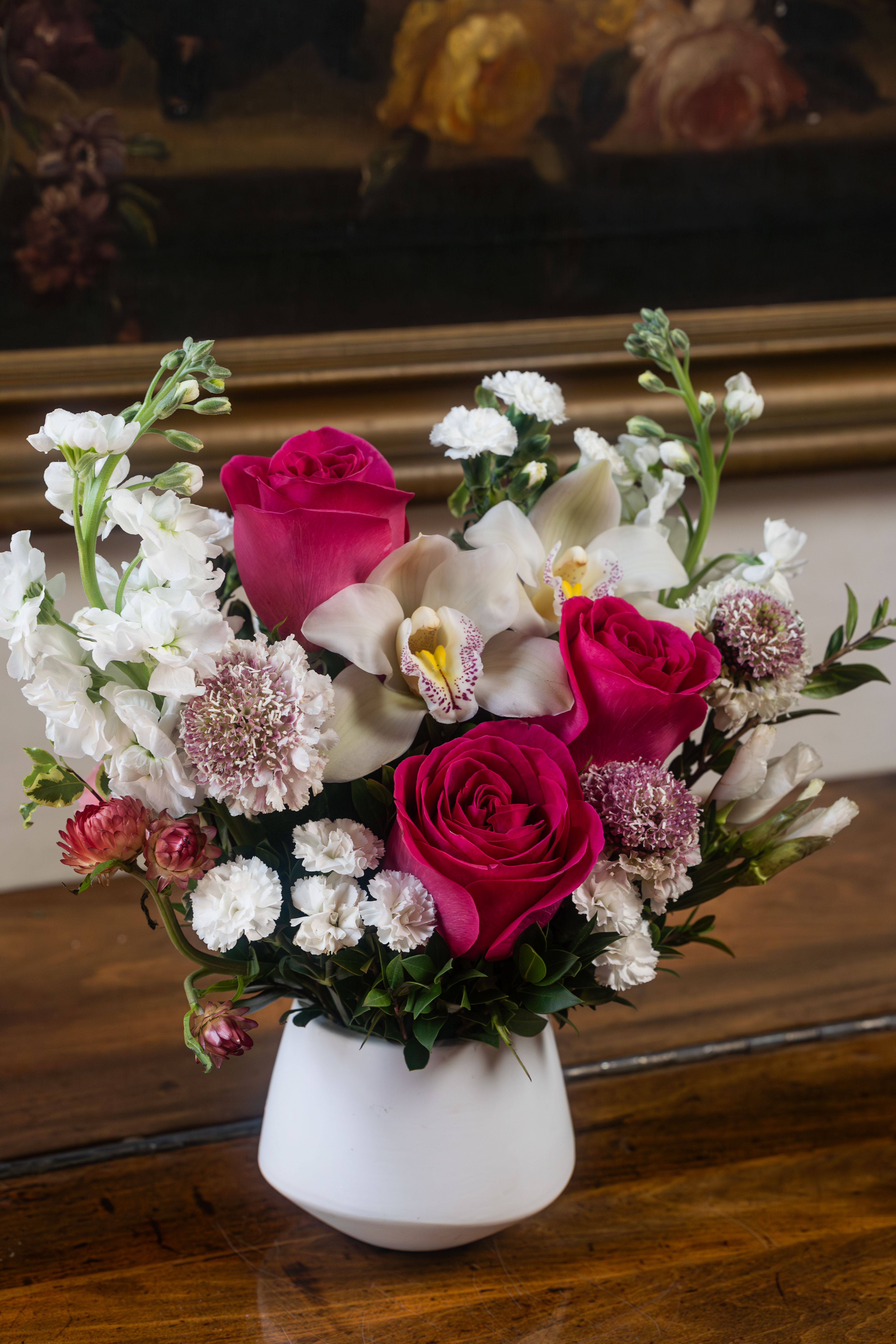 Pink Chic Mini Bouquet - This delightful pink and white mini bouquet, designed by Venetian Flowers, is a charming arrangement that exudes elegance and whimsy. Perfect for expressing love, gratitude, or celebration, this bouquet features a harmonious blend of vibrant and soft hues, creating a visually appealing contrast.  At the center of the bouquet, hot pink roses add a bold pop of color, symbolizing admiration and joy. Their lush, velvety petals create a striking focal point, drawing the eye and conveying a sense of warmth. Surrounding the roses are exquisite white orchids, which bring an air of sophistication and grace. Their delicate and intricate blooms symbolize beauty and strength, enhancing the bouquet's overall appeal.  Complementing these are fluffy white stock flowers, contributing a sweet fragrance and soft texture, while the charming white strawflowers add a touch of rustic elegance, providing a unique contrast with their papery petals. Delicate lisianthus, with its ruffled blooms, adds softness and depth, rounding out the bouquet with a graceful flourish.