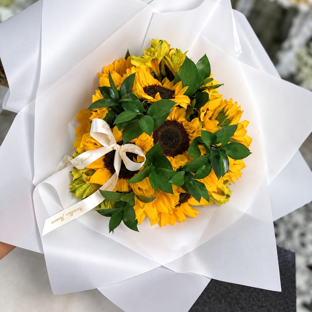 Bouquet of yellow sunflowers wrapped in white paper with a ribbon