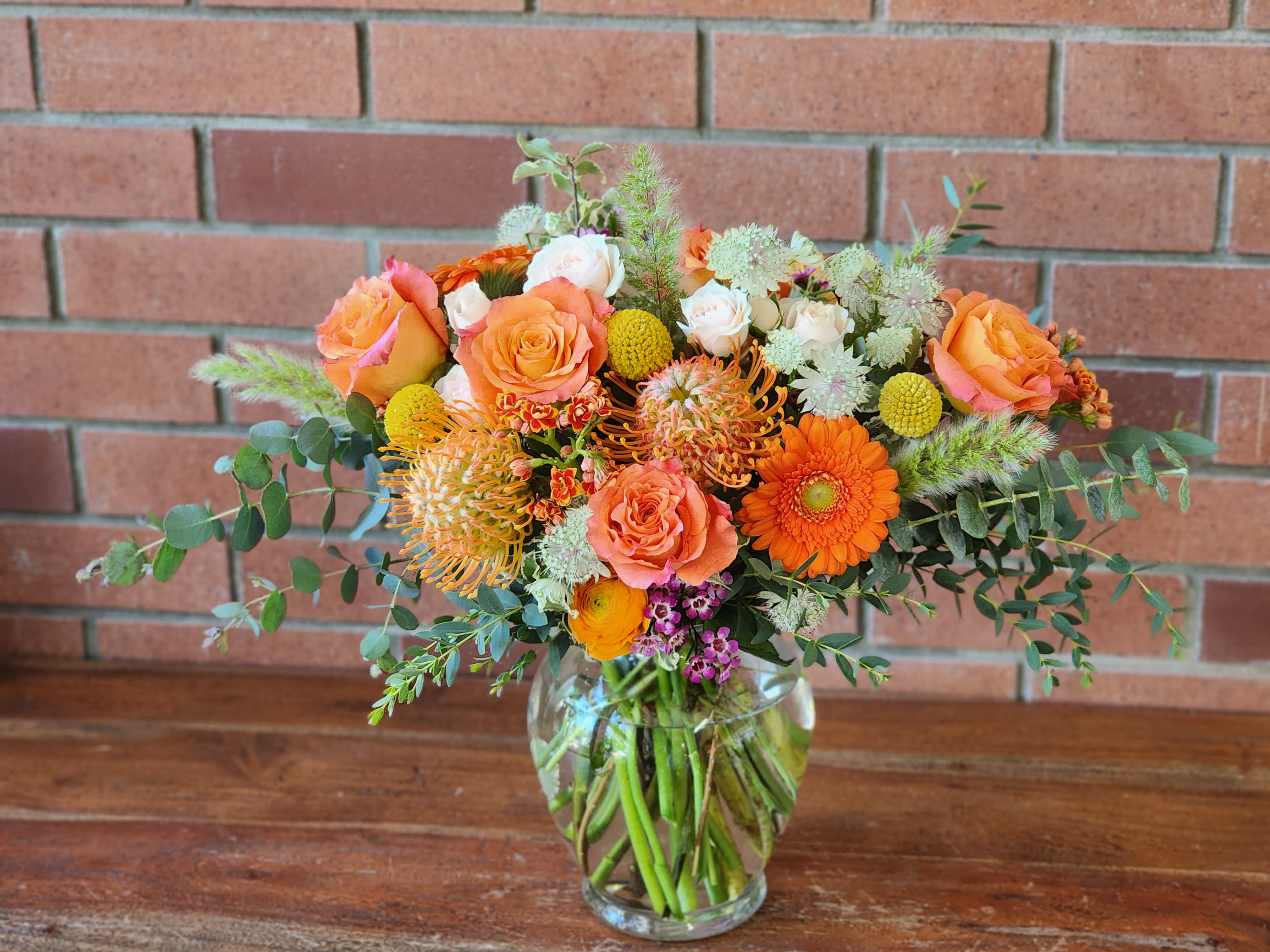 Bouquet of orange and peach flowers in a clear glass vase