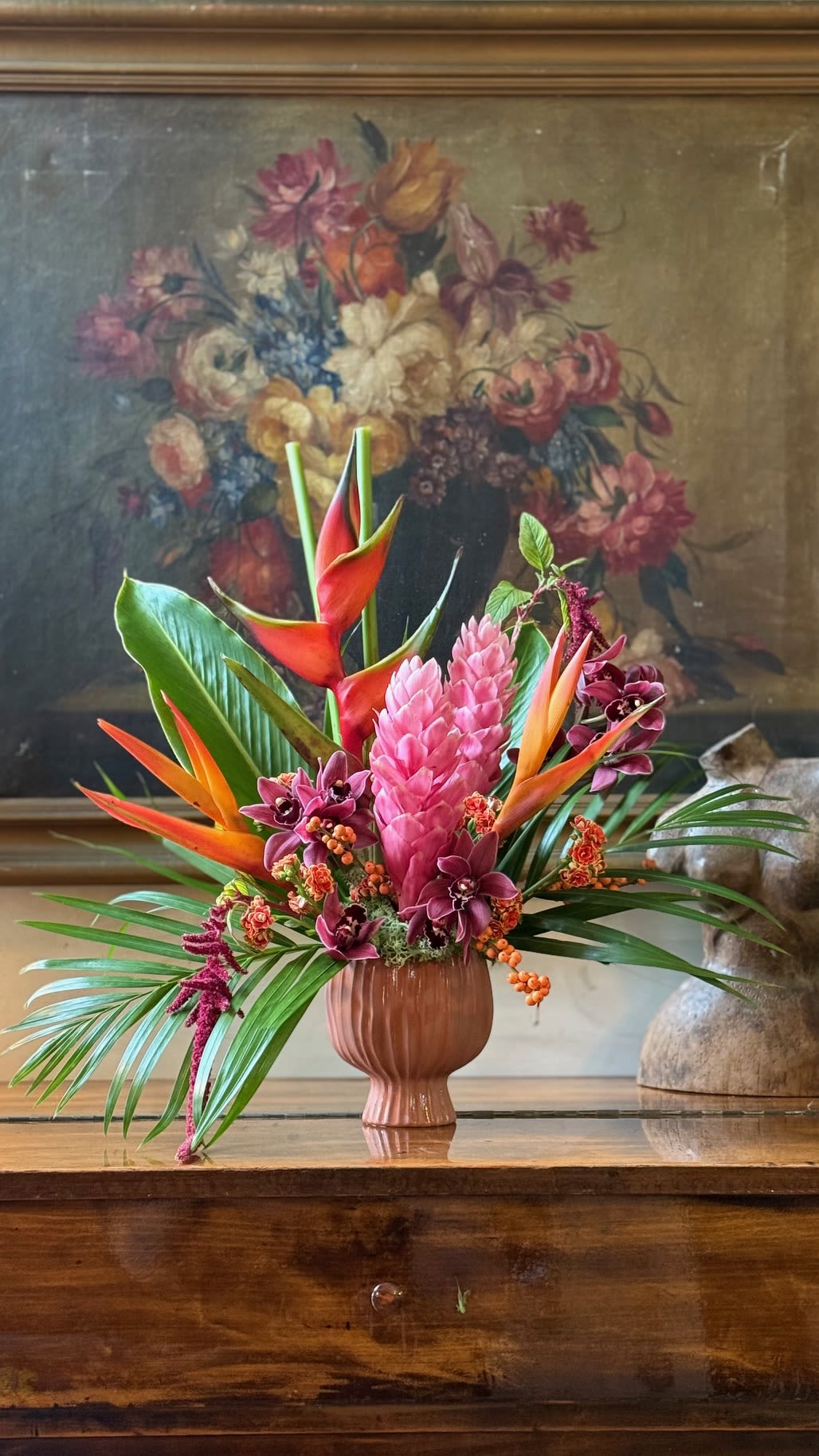 Tropical flower arrangement in a pink vase with pink and orange blooms
