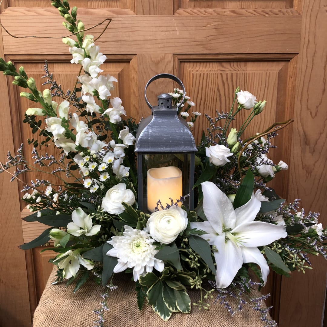 White floral arrangement with a lantern and candle