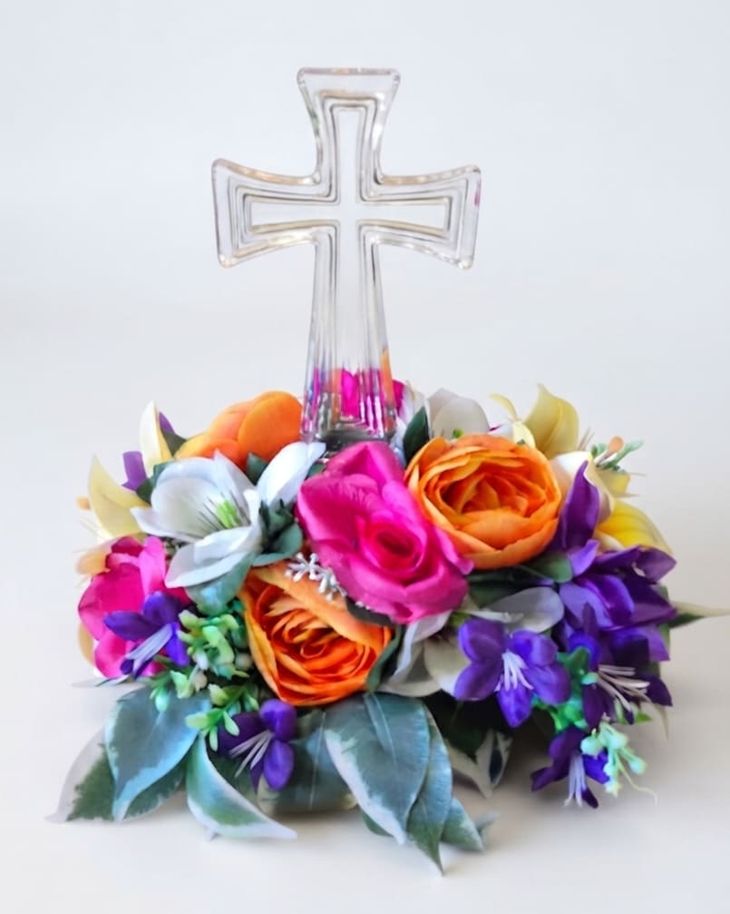 Floral arrangement with a clear cross topper and bright mixed blooms