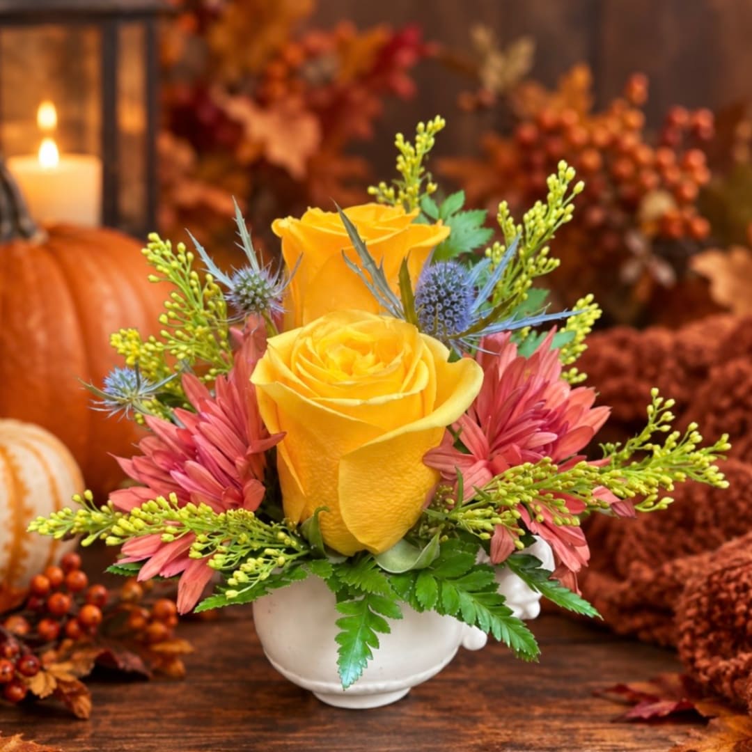 Yellow roses and pink flowers arranged in a white vase