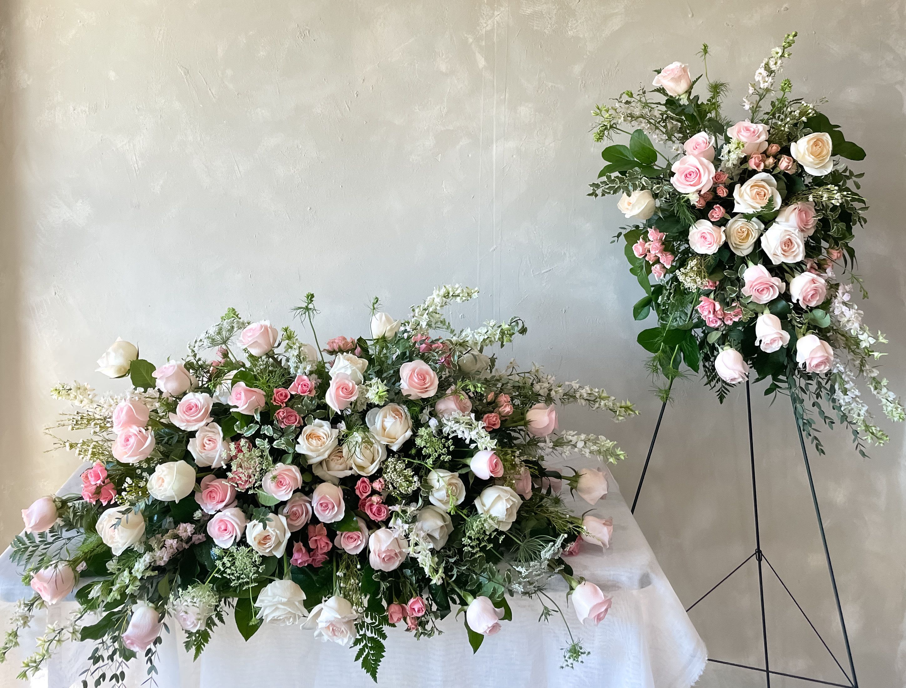 Pink and white rose arrangements, one on a table and one on a stand