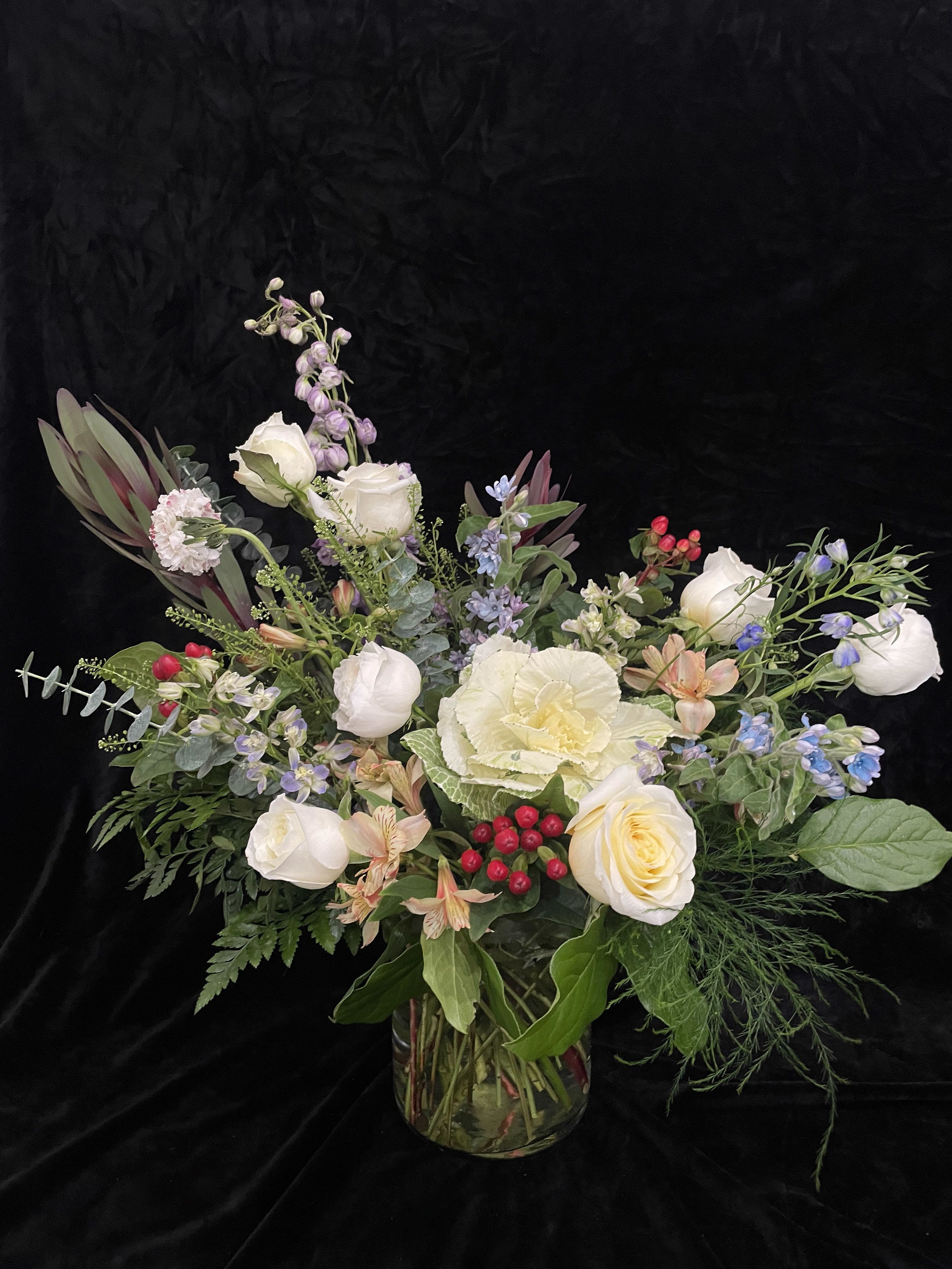 Mixed bouquet of white roses and pastel flowers in a glass vase