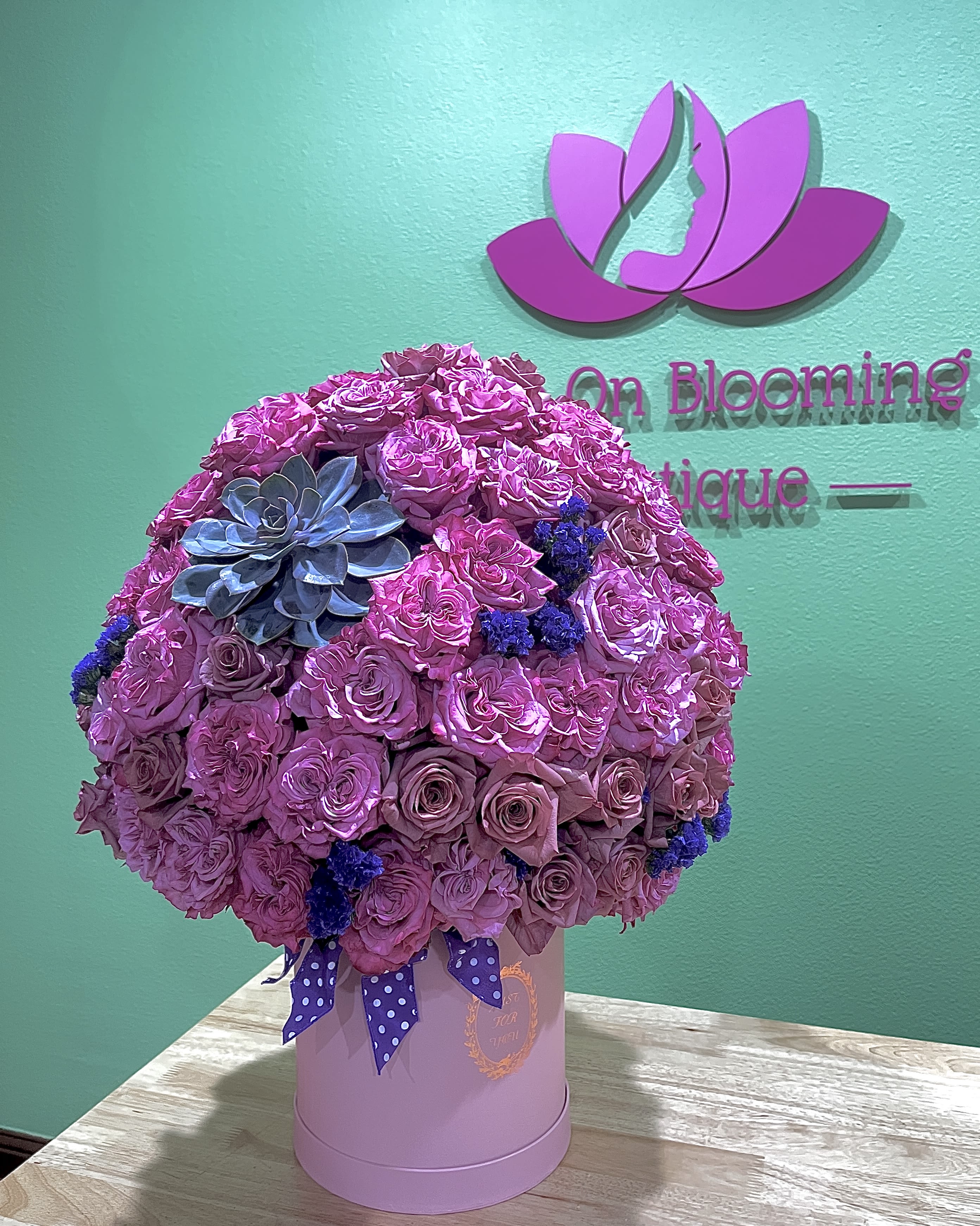 Pink rose arrangement in a round hat box with a succulent accent