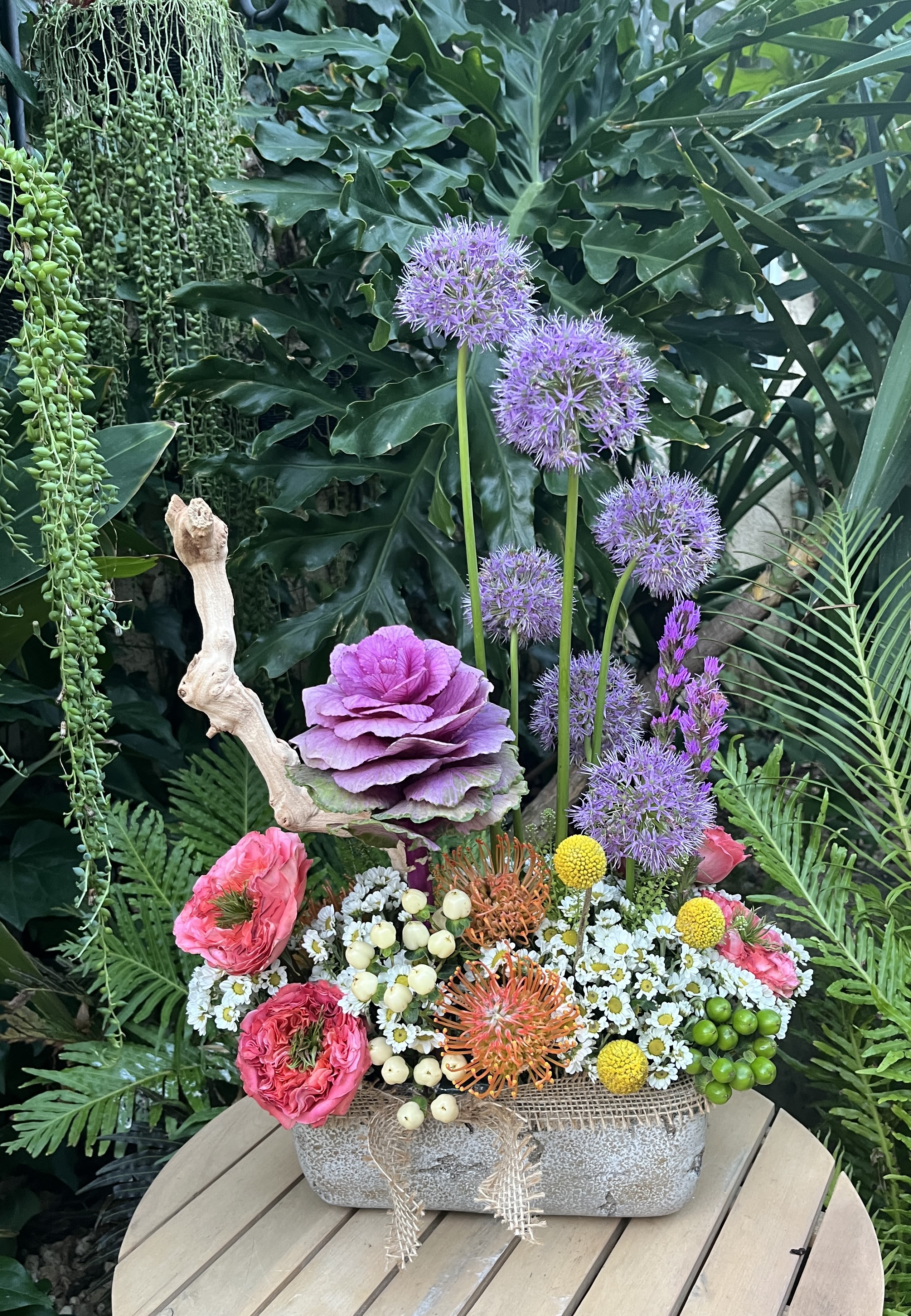 Mixed floral arrangement in a stone container with purple, pink, and white blooms